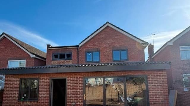 Rear house extension built by Kingdom Build in matched brickwork with wide dark aluminium sliding doors to the garden