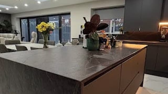 Open-plan kitchen and dining room completed by Kingdom Build, with a large island, stone worktop and rooflights above
