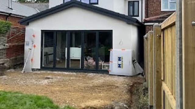 Single-storey rear extension built by Kingdom Build, finished in white render with dark grey window frames